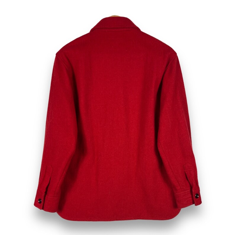 May include: A red long-sleeved shirt made of wool. The shirt has a button-up front and a collared neckline.