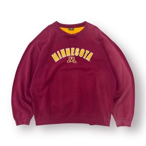 May include: Maroon crew neck sweatshirt with the word "MINNESOTA" arched across the chest in yellow lettering. Below the word is a yellow and maroon "M" logo. The sweatshirt has a yellow collar.