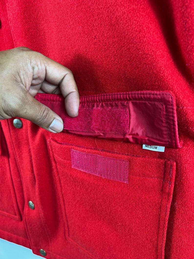 May include: Red fleece jacket with a large pocket on the front. The pocket has a velcro closure and a label that says "MEDIUM".