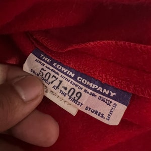 May include: A blue and white label with the text "THE EDWIN COMPANY" and "SOLD ONLY AT THE FINEST STORES." The label also has the text "LITTLE EDWIN Mr.50c 23xy" and "GARANTEED".