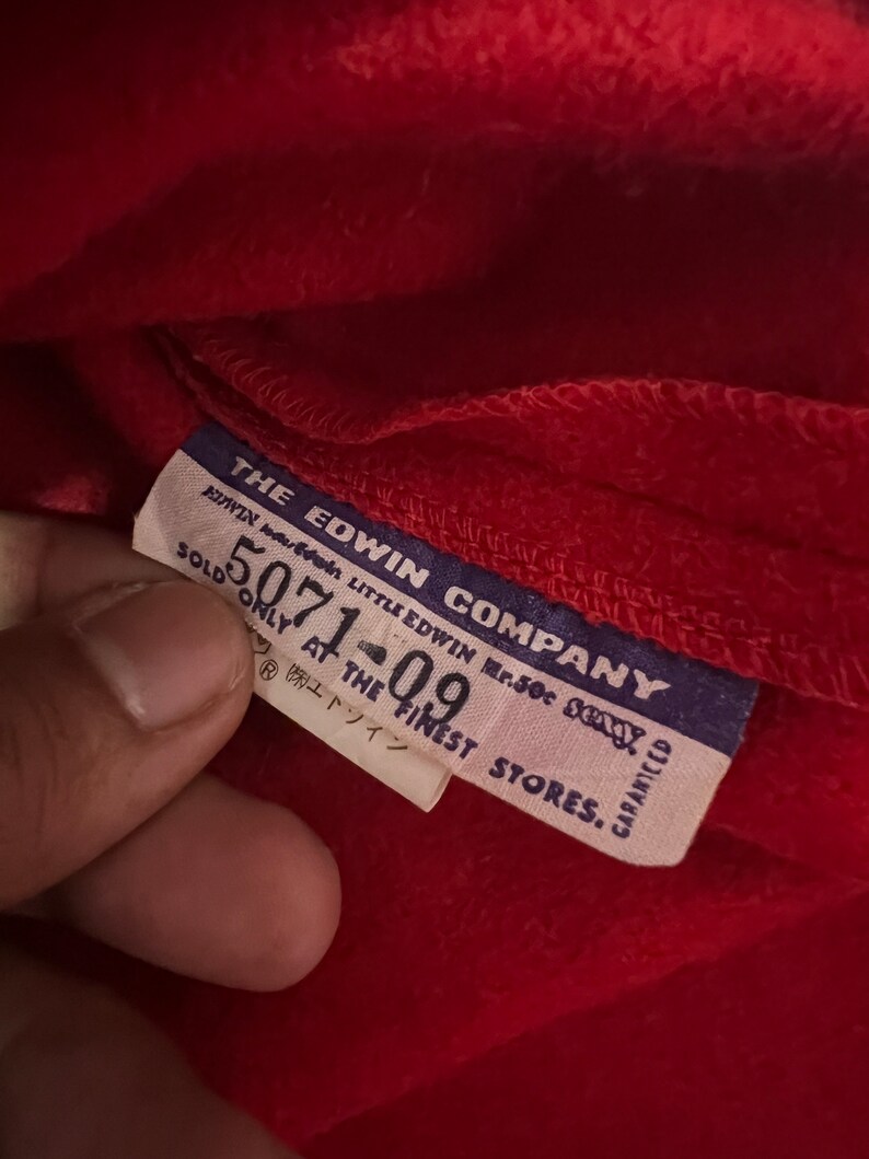 May include: A blue and white label with the text "THE EDWIN COMPANY" and "SOLD ONLY AT THE FINEST STORES." The label also has the text "LITTLE EDWIN Mr.50c 23xy" and "GARANTEED".