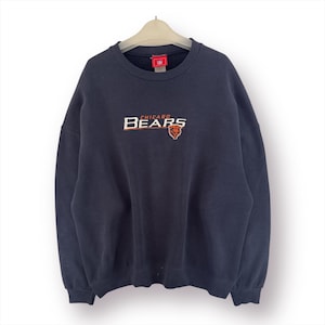 Puede incluir: Sudadera azul marino de los Chicago Bears con el nombre del equipo y el logotipo en naranja y blanco. La sudadera está colgada de una percha. La sudadera es de cuello redondo.