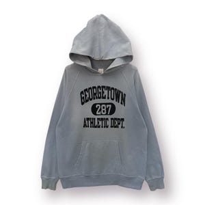 May include: A light blue hooded sweatshirt with the text "GEORGETOWN 287 ATHLETIC DEPT." printed in black.