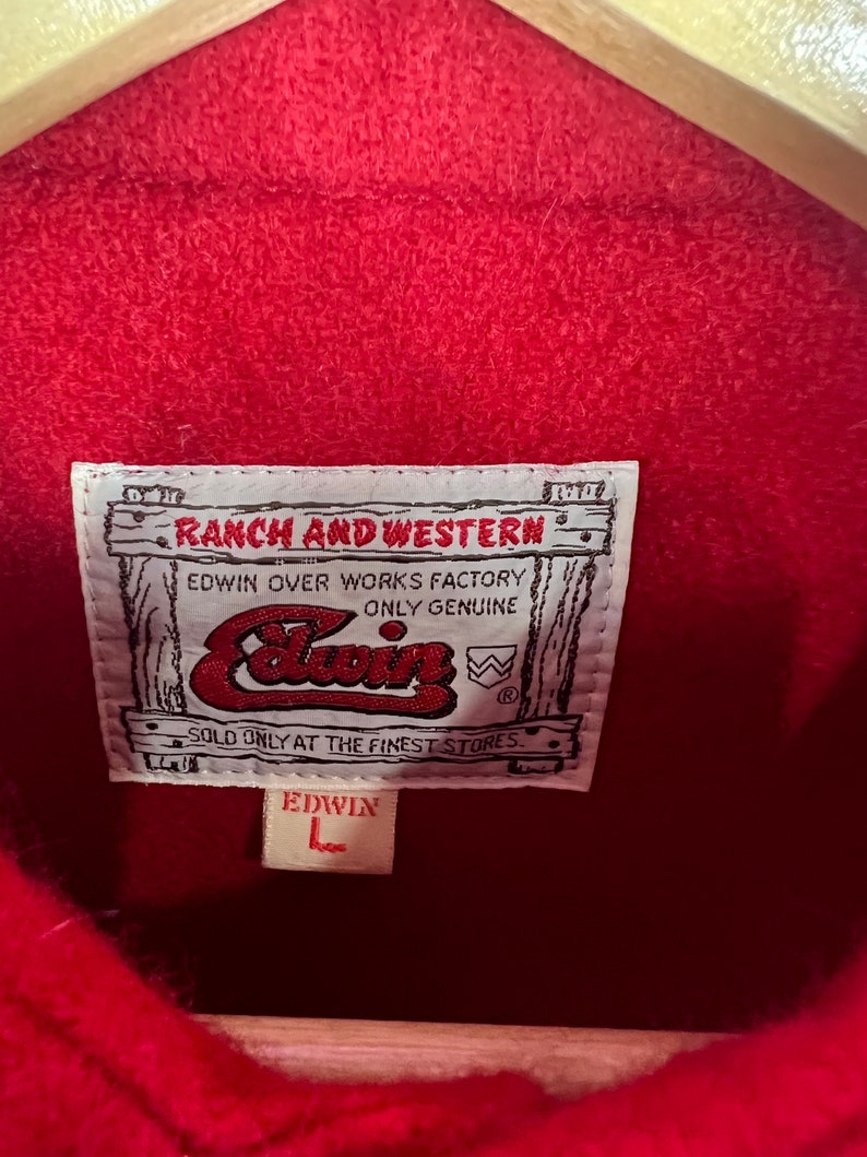 May include: Red denim jacket with a brown leather label that reads "RANCH AND WESTERN EDWIN OVER WORKS FACTORY ONLY GENUINE" and a white label that reads "EDWIN".