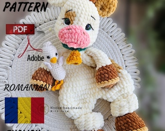 May include: Crochet pattern for a plush cow toy with brown and white fur, holding a small white chick. The pattern is available in both English and Romanian languages. The pattern is available as a PDF download.