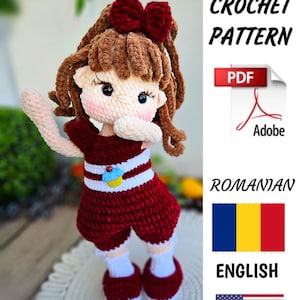 May include: Crochet pattern for a red and white doll with brown hair and a red bow. The pattern is available in both English and Romanian. PDF download.