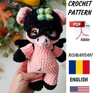 May include: Crochet pattern for a pink pig wearing a black mask with a green flower on top. The pattern is available in both English and Romanian.
