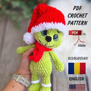 May include: A green crocheted Grinch doll wearing a red Santa hat with white trim and a red scarf. The doll has black eyes and a black nose. The image also includes text that says "PDF Crochet Pattern" and flags for Romanian and English.