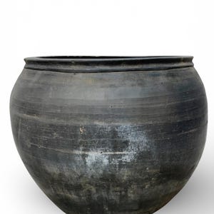 May include: A white ceramic mug with a black handle and the text "But First, Coffee" in a bold, black font. The mug is set against a blurred background, suggesting a cozy setting.