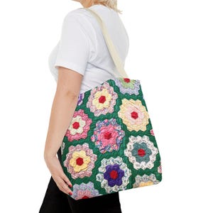 May include: A floral tote bag with a green background and colorful flower patterns. The bag has a cream-colored strap and is carried over the shoulder. The flowers are in shades of pink, yellow, and purple.