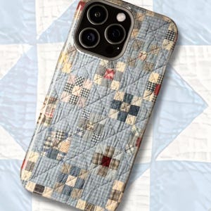 Puede incluir: Una funda para smartphone con un patr&oacute;n de tela acolchada sobre un fondo de cuadros vichy azul claro y peque&ntilde;os parches cuadrados en tonos azul, blanco, rojo y beige. El dise&ntilde;o presenta una textura de costuras en forma de rombos.
