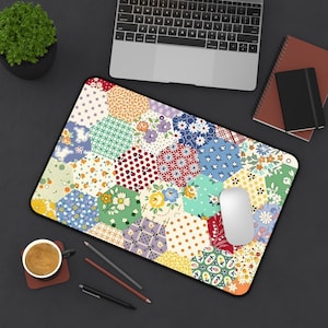 May include: A colorful mousepad with a patchwork design featuring various floral and geometric patterns in red, blue, yellow, and green. The mousepad is rectangular with a black border, and a white mouse rests on it.