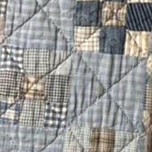 Puede incluir: Una colcha de patchwork que presenta una variedad de cuadrados de tela en azul, blanco y beige con patrones de cuadros, vichy y lisos. El textil est&aacute; cosido con un dise&ntilde;o de acolchado de rejilla diagonal, destacando un solo cuadrado rojo oscuro.