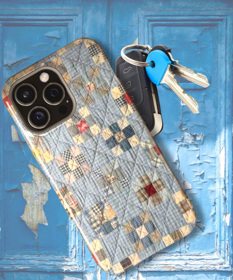 Puede incluir: Una funda para smartphone con un patr&oacute;n de tela acolchada de cuadros en tonos azul claro, beige y rojo, junto a una llave de coche negra con una tapa de pl&aacute;stico azul brillante y dos llaves de metal plateado en un anillo de metal.
