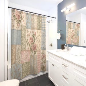 May include: A shower curtain featuring a patchwork design of various floral, damask, and gingham patterns in muted shades of pink, blue, green, and beige. The curtain hangs from a black rod with metal rings, covering a bathtub area in a bathroom.