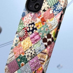 Op de afbeelding: Een smartphonehoesje met een kleurrijk patchworkontwerp bestaande uit diverse kleine vierkante stofpatronen in tinten roze, groen, blauw, geel en wit, met een zwarte uitsparing voor de camera en knoppen aan de zijkant van de behuizing.