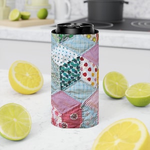 May include: A slim, cylindrical can cooler featuring a colorful patchwork quilt pattern. The design consists of various fabric squares in shades of blue, pink, red, and white, displaying diverse floral, striped, and polka dot prints across the surface.