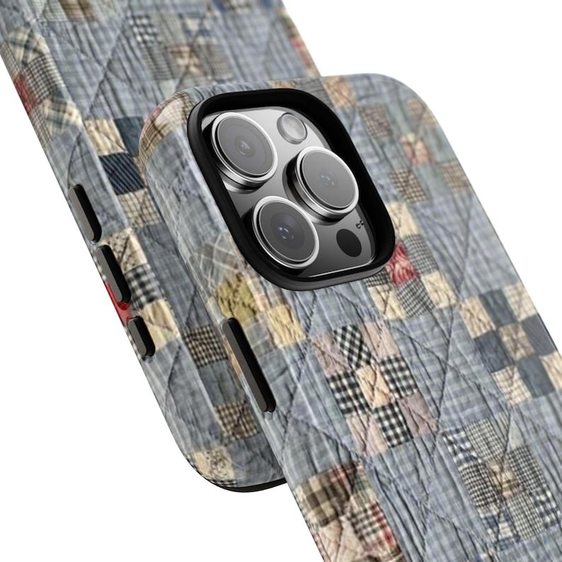Puede incluir: Una funda protectora para tel&eacute;fono con un patr&oacute;n de tela acolchada en tonos azul, gris y crema. El dise&ntilde;o muestra una cuadr&iacute;cula de peque&ntilde;os cuadrados con diversas texturas de cuadros. La funda tiene un recorte negro para la c&aacute;mara.