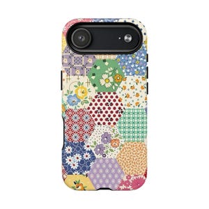May include: A colorful phone case featuring a patchwork design. The case is covered in hexagonal patterns of various colors and floral prints, including red polka dots, blue flowers, and green geometric shapes. The camera lens is visible at the top.