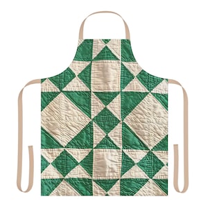 May include: Green and cream-colored apron with a geometric quilt pattern. The apron features a repeating design of green triangles and cream-colored squares. The apron has tan straps for the neck and waist.