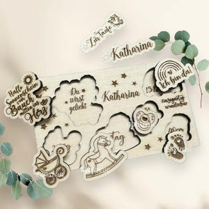 May include: Wooden puzzle with a variety of cutouts and text, including "Hallo Sonnenschein vom Bauch mitten ins Herz", "Du * wirst geliebt", "Katharina", "Zur Taufe", "Katharina 15.1", "Ich bin da!", "Tag", "53 cm", "einzigartig wunderbar", "40 cm", and a baby footprint.