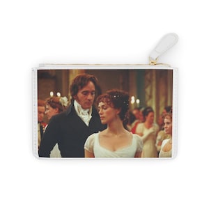 Puede incluir: Bolsa rectangular blanca con cremallera que presenta una escena de un drama de época. La imagen muestra a un hombre y una mujer con vestimenta formal, rodeados de otras figuras en un salón de baile. La bolsa tiene un tirador blanco y cremallera dorada.