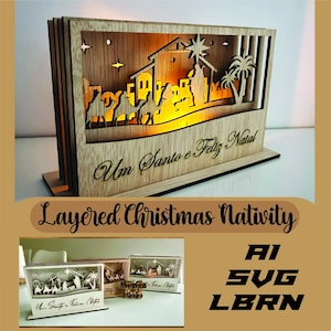 May include: A layered wooden Christmas nativity scene with a warm, glowing interior. The design features silhouettes of the holy family, camels, and palm trees. The text "Um Santo e Feliz Natal" is visible. The words "Layered Christmas Nativity" are also present.