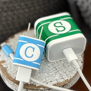 May include: Two white phone chargers with personalized labels. One charger has a green label with the letter "S" and the other has a blue label with the letter "C".