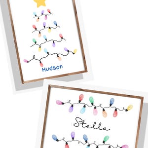 Könnte beinhalten: Zwei gerahmte Drucke mit Weihnachtsmotiv. Einer zeigt einen Baum aus bunten Lichtern und einem gelben Stern, darunter der Name "Hudson". Der andere Druck zeigt eine Lichterkette mit dem Namen "Stella".