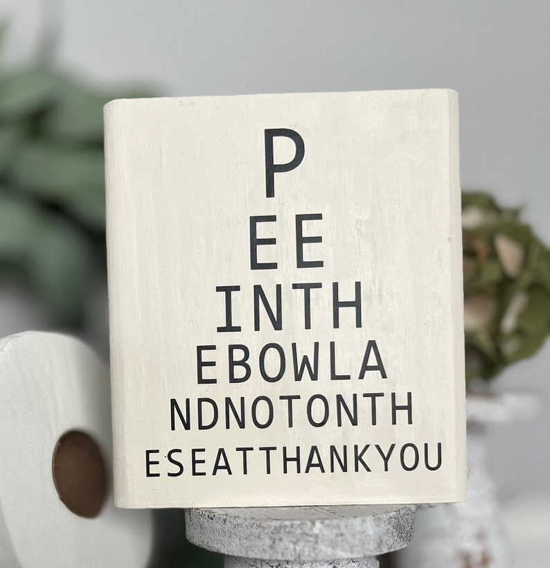 May include: White wooden sign with black text that reads "Pee in the bowl and not on the seat thank you".