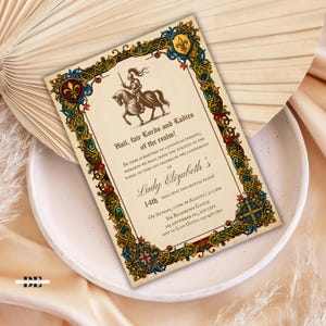 May include: A rectangular invitation card featuring a medieval-style border in gold, blue, and red with a knight on horseback at the top. The text reads: Hail, fair Lords and Ladies of the realm! Be thee summoned to a joyous gathering, Lady Elizabeth's 14th year upon this mortal plane! On Sunday, 07th of August, 2:00pm, Sir Richmond Castle, 123 Anywhere St., Any City, RSVP to Lady Olivia: 123-456-7890.