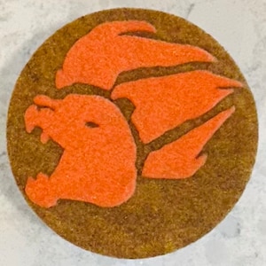 May include: A round, brown cookie with an orange, stylized dragon design.
