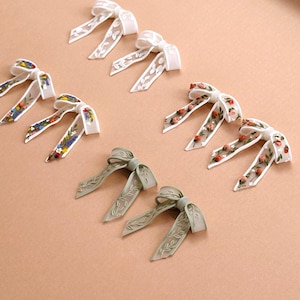 May include: A set of three ceramic mugs with a speckled, matte finish. The mugs are in shades of cream, light gray, and dark gray. Each mug has a simple, minimalist design and a rounded handle. The mugs are likely for coffee or tea.