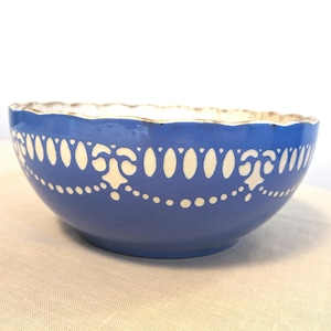May include: A blue ceramic bowl with a white scalloped edge and a white decorative design around the rim.