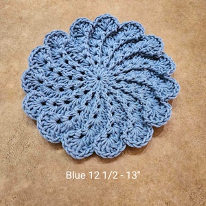 May include: A light blue, crocheted doily with a scalloped edge. The doily is approximately 12.5 to 13 inches in diameter. The text "Blue 12 1/2 - 13" is printed on the bottom of the image.