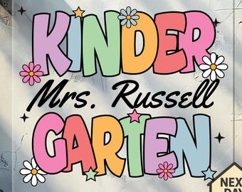 May include: A colorful sign with the words "KINDER Mrs. Russell GARTEN" in large, bubble letters. The letters are in shades of pink, orange, green, and blue, with flower and star accents. The sign also includes a "NEXT DAY SHIPPING" icon.