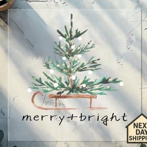 May include: A watercolor illustration of a Christmas tree on a sled, with the words "merry + bright" in black script. The tree is green with white lights. A small house icon with "NEXT DAY SHIPPING" is in the bottom right corner.