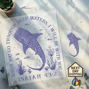 Op de afbeelding: Een lichtpaarse afbeelding met een walvishaai-ontwerp en de tekst "WHEN YOU GO THROUGH DEEP WATERS, I WILL BE WITH YOU. ISAIAH 43:2". Bevat een kleinere walvishaai-afbeelding en een "NEXT DAY SHIPPING"-logo.