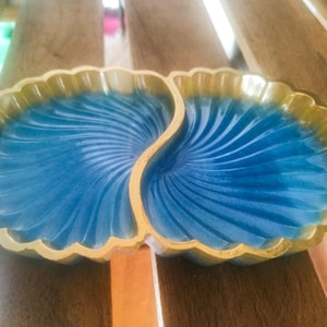 May include: A blue and gold shell-shaped dish with two compartments. The dish is made of ceramic and has a glossy finish.