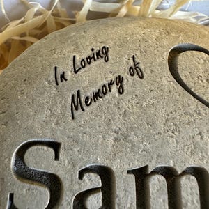 May include: A gray stone memorial with the text "In Loving Memory of Sam" engraved on it.