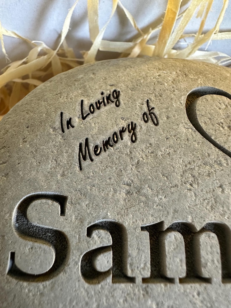 May include: A gray stone memorial with the text "In Loving Memory of Sam" engraved on it.