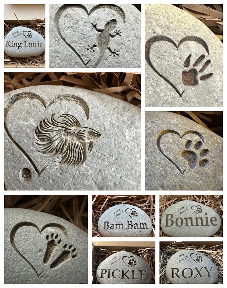 May include: A collection of personalized pet memorial stones with various engravings, including paw prints, a lizard, a fish, and names like "King Louie", "Bam Bam", "Bonnie", "Pickle", and "Roxy".