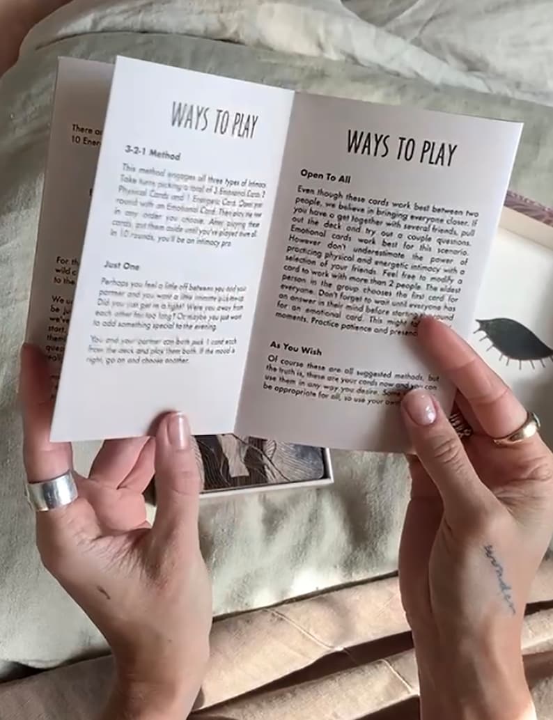 Może przedstawiać: Biała książeczka otwarta na stronie tytułowej z napisem "Ways to Play". Książeczka zawiera instrukcje do gry w karty. Książeczka jest otwarta, aby ujawnić tekst wewnątrz, kt&oacute;ry zawiera r&oacute;żne sposoby gry.