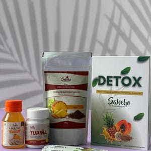 May include: Assortment of health products including a bottle of orange liquid labeled "Vinagre Pitaya", a white bottle of "Tupiña" pills, a bag of "Fibra de Manzana" with pineapple, and a box of "Detox" products. Several small packets are also visible.