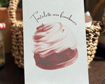 May include: A rectangular white card with a textured surface featuring a printed illustration of a raspberry tart topped with cream. The text "Tartelette aux framboises" is printed in a dark brown script font above the dessert illustration.
