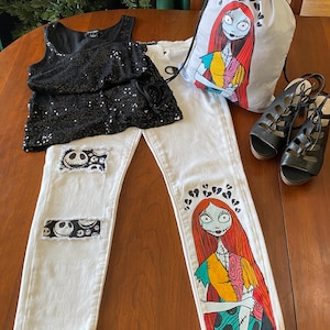 May include: White denim jeans with a hand-painted image of Sally from The Nightmare Before Christmas on one leg and a patch with Jack Skellington's face on the other leg. A black sequined tank top and a grey drawstring bag with a printed image of Sally are also included.