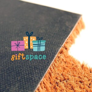 a close-up view of a brown textured surface, possibly a carpet or mat, with a circular logo featuring a gift box and the text "giftspace" on it.