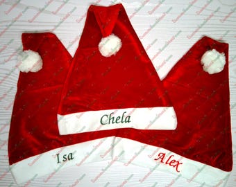 May include: Three red Santa hats with white trim and white pom-poms. The hats are personalized with the names "Chela", "Isa", and "Alex" in green embroidery.