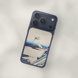 May include: A navy blue phone case featuring a Japanese-style landscape design. The case showcases a mountain scene with a kite in the sky, rendered in shades of blue, pink, and green. The phone case has a matte finish.