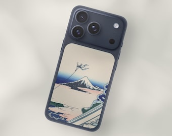May include: A navy blue phone case featuring a Japanese-style landscape design. The case showcases a mountain scene with a kite in the sky, rendered in shades of blue, pink, and green. The phone case has a matte finish.
